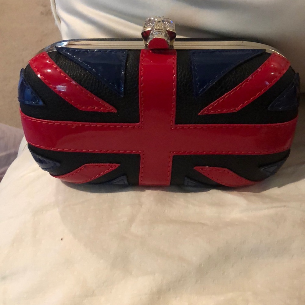 Black clutch with red and navy patent detailing. Rhinestone skull on top
